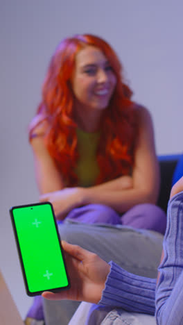 Vertical-Video-Of-Group-Of-Gen-Z-Friends-Sitting-On-Sofa-Eating-Home-Delivery-Takeaway-Pizza-And-Using-Mobile-Phones